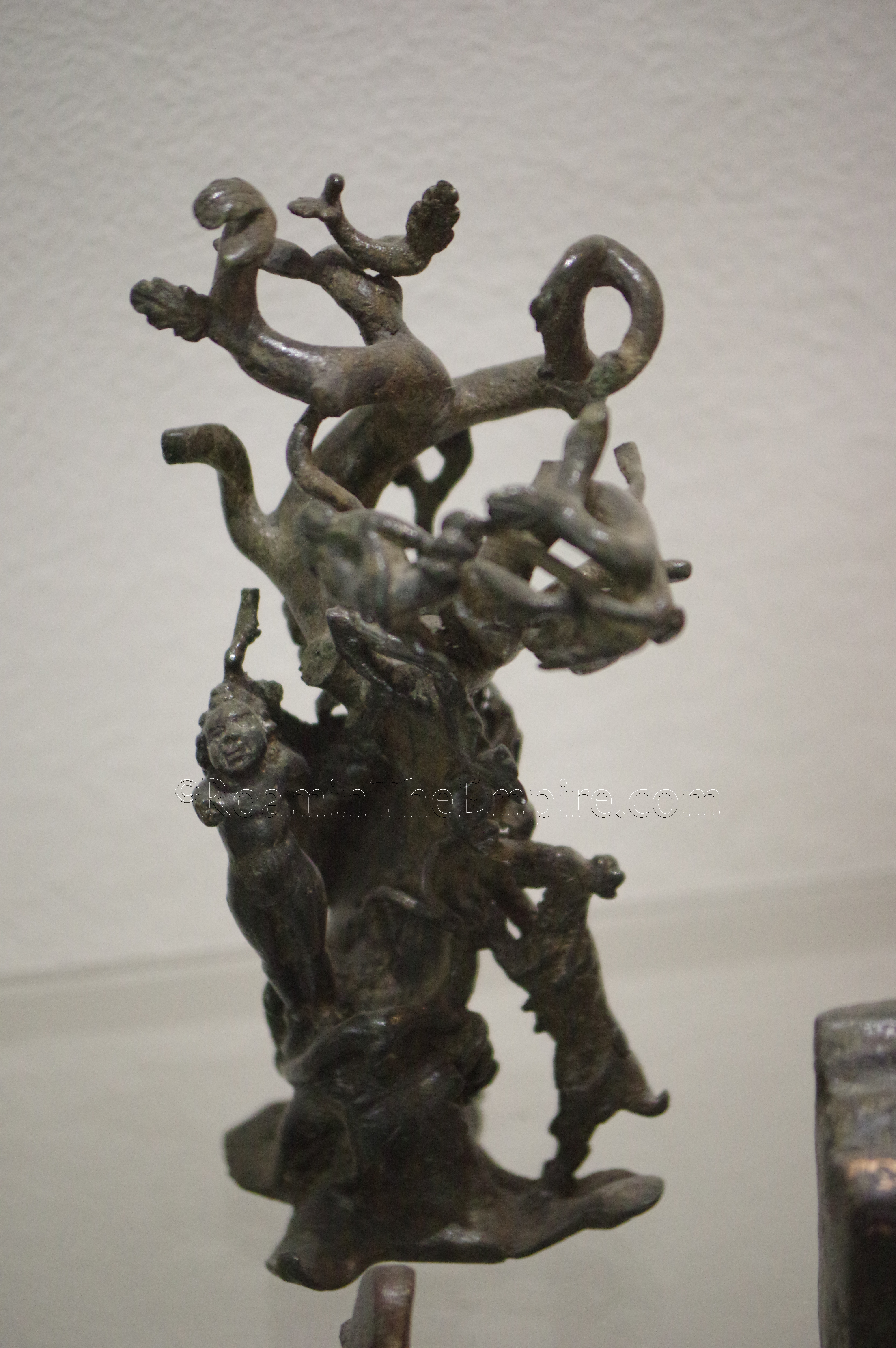 Bronze decorative element with erotes around a tree. Dated to the 3rd century CE. Aquincum Archaeological Museum.