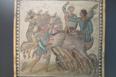 Mosaic of a quadriga and victorious charioteer of the veneta. In front, the sparsor prepares to water the horses. Dated to the 3rd century CE, from Rome.