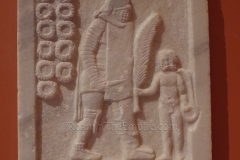 Funerary stele of the secutor gladiator Trypheros, erected by his son Alexandros, depicting handing him a palm branch. The eleven wreathes represent Trypheros' victories. Archaeological Museum of Patras.