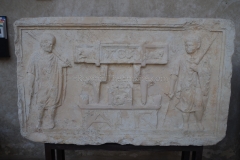 Funerary relief of a curulis decorated with masonry tools (indicating the deceased's trade) situated between two lictors. Dated to the 1st century CE. From Verona, now in the Museo Lapidario Maffeiano .