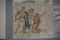 Detail of the gladiator mosaic in the Museo Archeologico al Teatro Romano. A retarius is defeated by a secutor gladiator, but is spared death by the referee.
