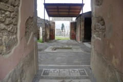 Tablinum of the House of Marcus Cassius Blandinus at Pompeii, viewed across the atrium from the fauces. A garden is visible beyond the tablinum.d